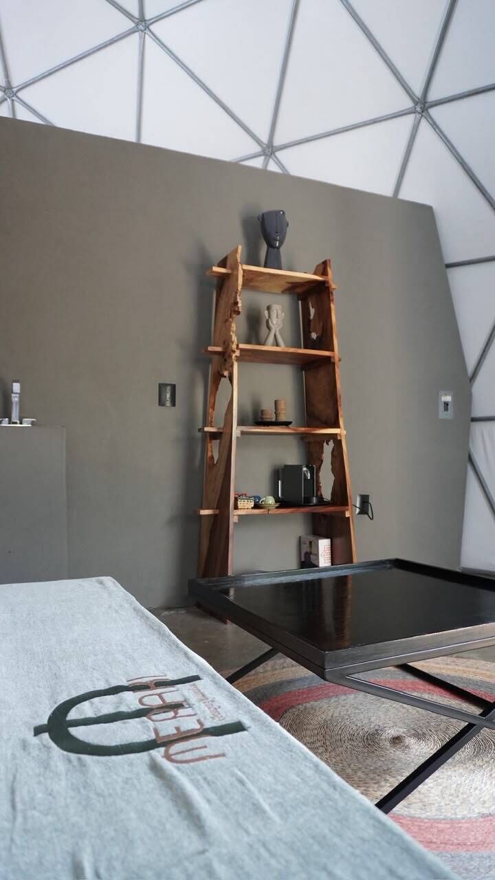 A room with a bed, a wooden ladder shelf, and a glass coffee table.