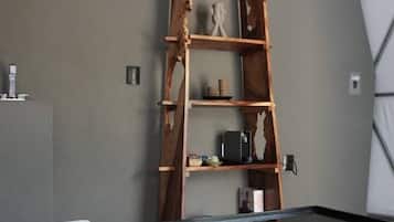 A room with a bed, a wooden ladder shelf, and a glass coffee table.