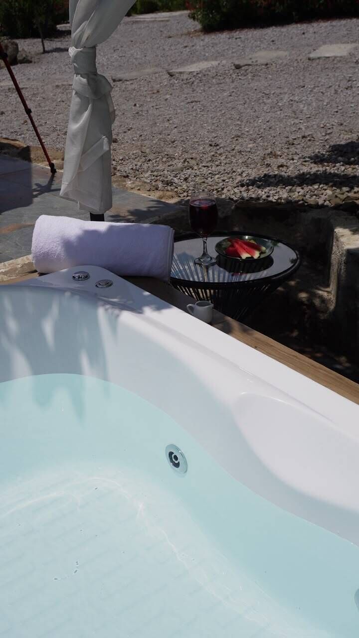 A spa area with a hot tub, a towel, and a small table with a glass and fruit.