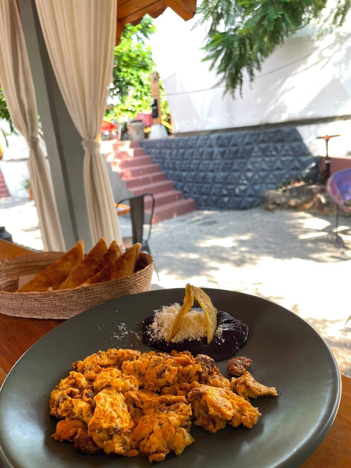 Una mesa de comedor con un plato de comida, una cesta de pan y una silla.
