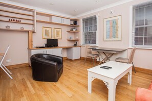 A modern living room with a leather sofa, a dining table, and a TV. - Sunlit 1BDR Near Westminster and Big Ben (London)