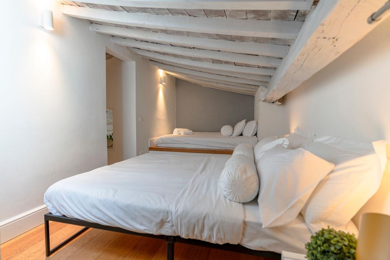 A bedroom with a bed, a bedside table, and a small plant.