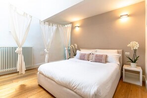 Een slaapkamer met een groot bed, een nachtkastje, een wandlamp en een radiator.