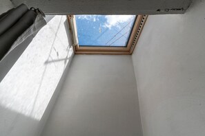 Ein Oberlicht in einem Raum mit weißen Wänden und sichtbarer Holzbauweise.