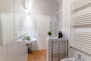 Een moderne badkamer met een wit wastafelmeubel, spiegel en handdoekrek.