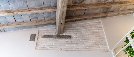 Et loft med synlige træbjælker og en murstensvæg.