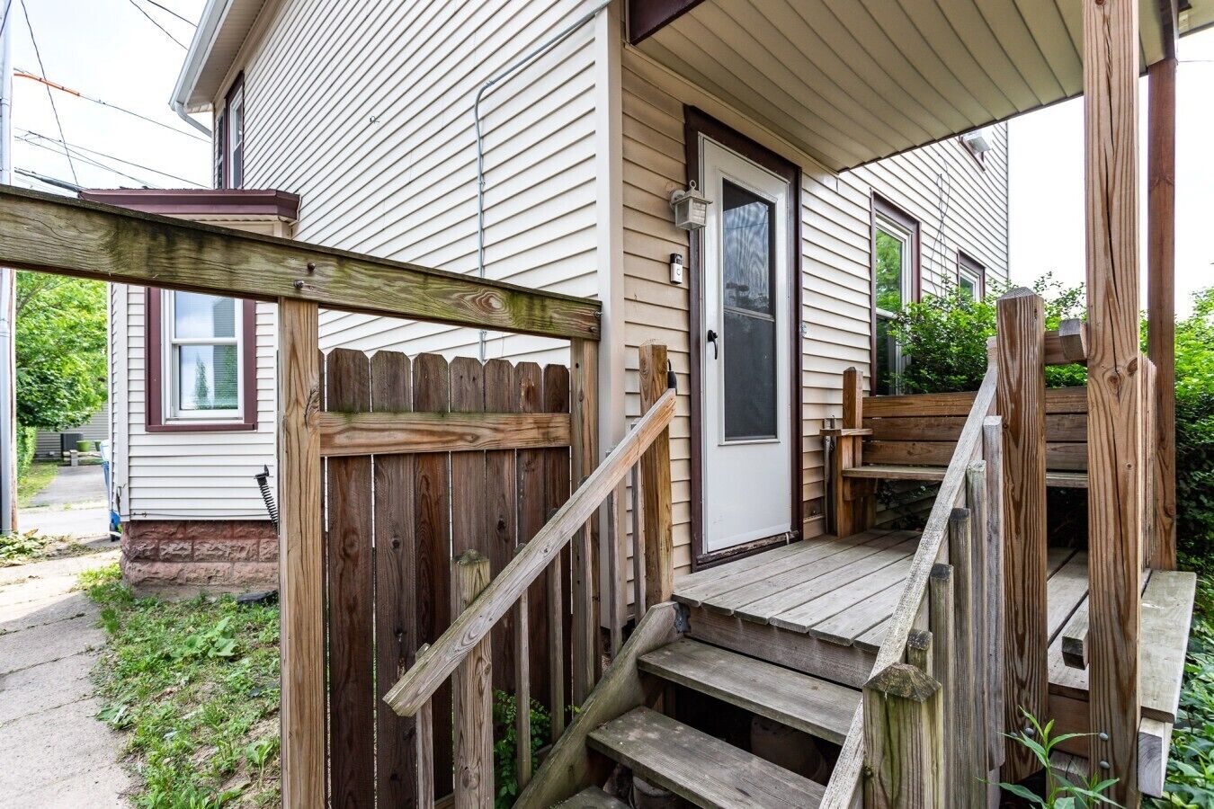 A wooden deck with a staircase leading to a house entrance.