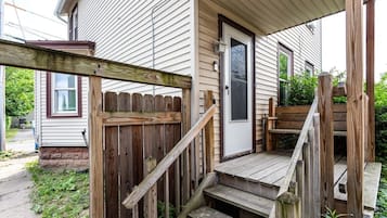 A wooden deck with a staircase leading to a house entrance.