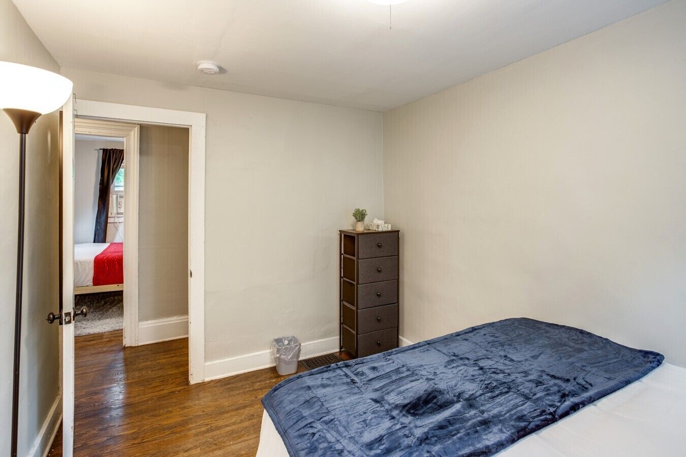 Ein Schlafzimmer mit einem Bett, einem Schminktisch und einer Tür zu einem anderen Raum.