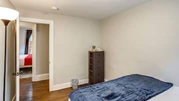 Ein Schlafzimmer mit einem Bett, einem Schminktisch und einer Tür zu einem anderen Raum.