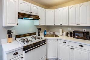 A kitchen with white cabinetry, a stove, a microwave, and a sink. - Downtown Rochester Home / 3 Bedrooms, Parking (Rochester)