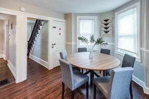 A dining area with a round table, four chairs, and a vase with greenery. - Downtown Rochester Home / 3 Bedrooms, Parking (Rochester)