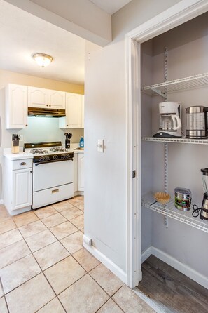 A kitchen with white cabinets, a stove, and a coffee maker on a shelf. - Downtown Rochester Home / 3 Bedrooms, Parking (Rochester)
