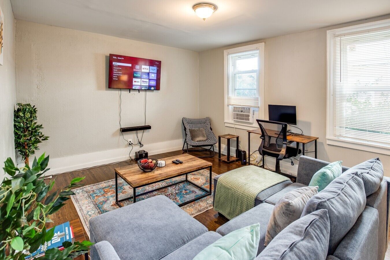 A living room with a TV, a desk with a computer, a couch, and a coffee table.