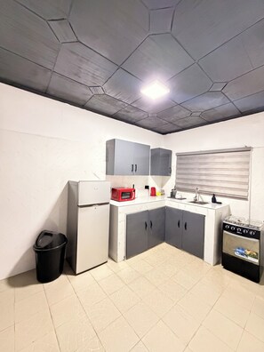 A compact kitchen with a refrigerator, microwave, stove, and cabinets. - City Centre Oasis (Accra)