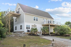 A two-story house with a balcony, a front porch, and a small garden area. - Spacious 4-bedroom house in serene Surf City with AC (Surf City)