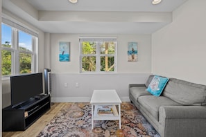 A living room with a flat-screen TV, a grey sofa, a white coffee table, and a patterned rug. - Spacious 4-bedroom house in serene Surf City with AC (Surf City)