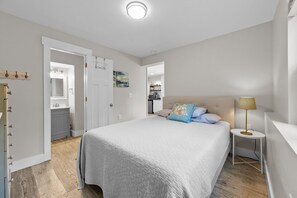 A bedroom with a bed, bedside table, and a nightstand. - Spacious 4-bedroom house in serene Surf City with AC (Surf City)