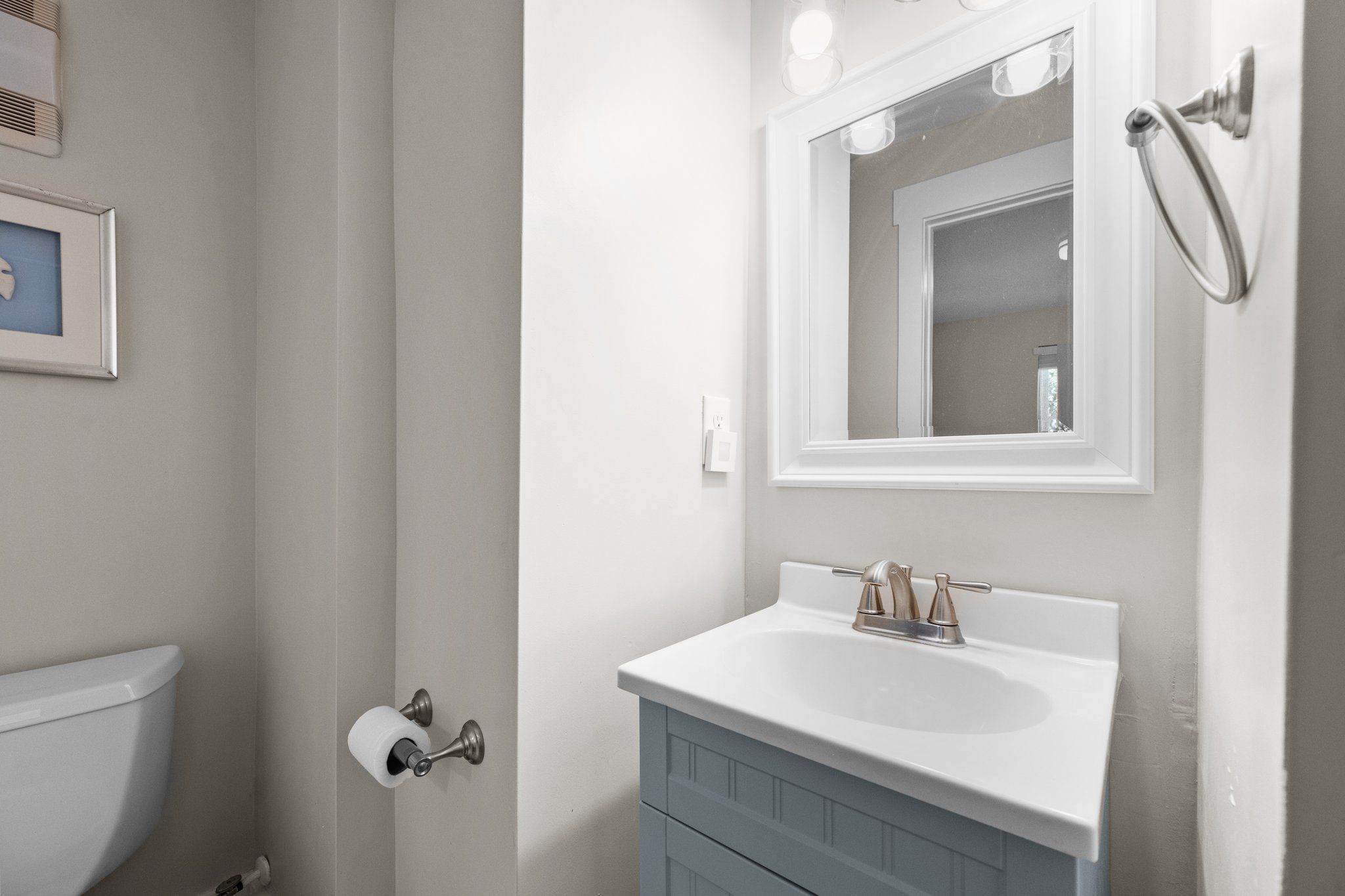 A bathroom with a white sink, a mirror, a towel rack, and a toilet.