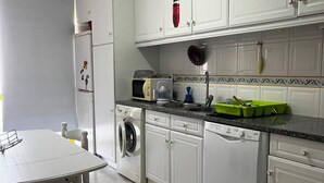 A kitchen with white cabinets, a washing machine, a microwave, and a dishwasher. - Apartment with Pool View and Private Balcony (Quarteira)
