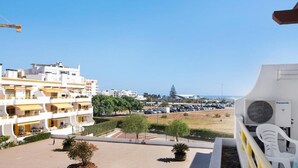 A residential building with multiple balconies, a parking lot, and a view of the sea. - Apartment with Pool View and Private Balcony (Quarteira)