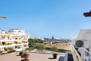 Ein Wohngebäude mit mehreren Balkonen, einem Parkplatz und Blick auf das Meer.
