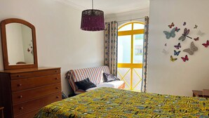 A bedroom with a bed, dresser, and a window with curtains. - Apartment with Pool View and Private Balcony (Quarteira)