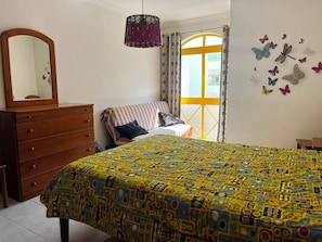 Ein Schlafzimmer mit Bett, Kommode und einem Fenster mit Vorhängen.