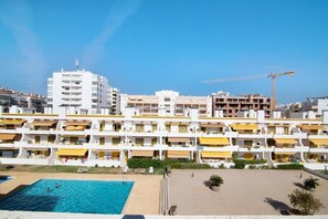 Ein mehrstöckiges Hotel mit Balkonen, einem Schwimmbad und einem Baukran im Hintergrund.