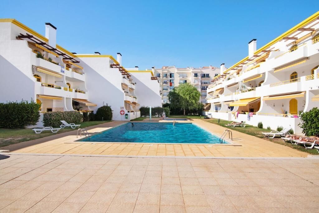 A swimming pool area with sun loungers and a clear sky.