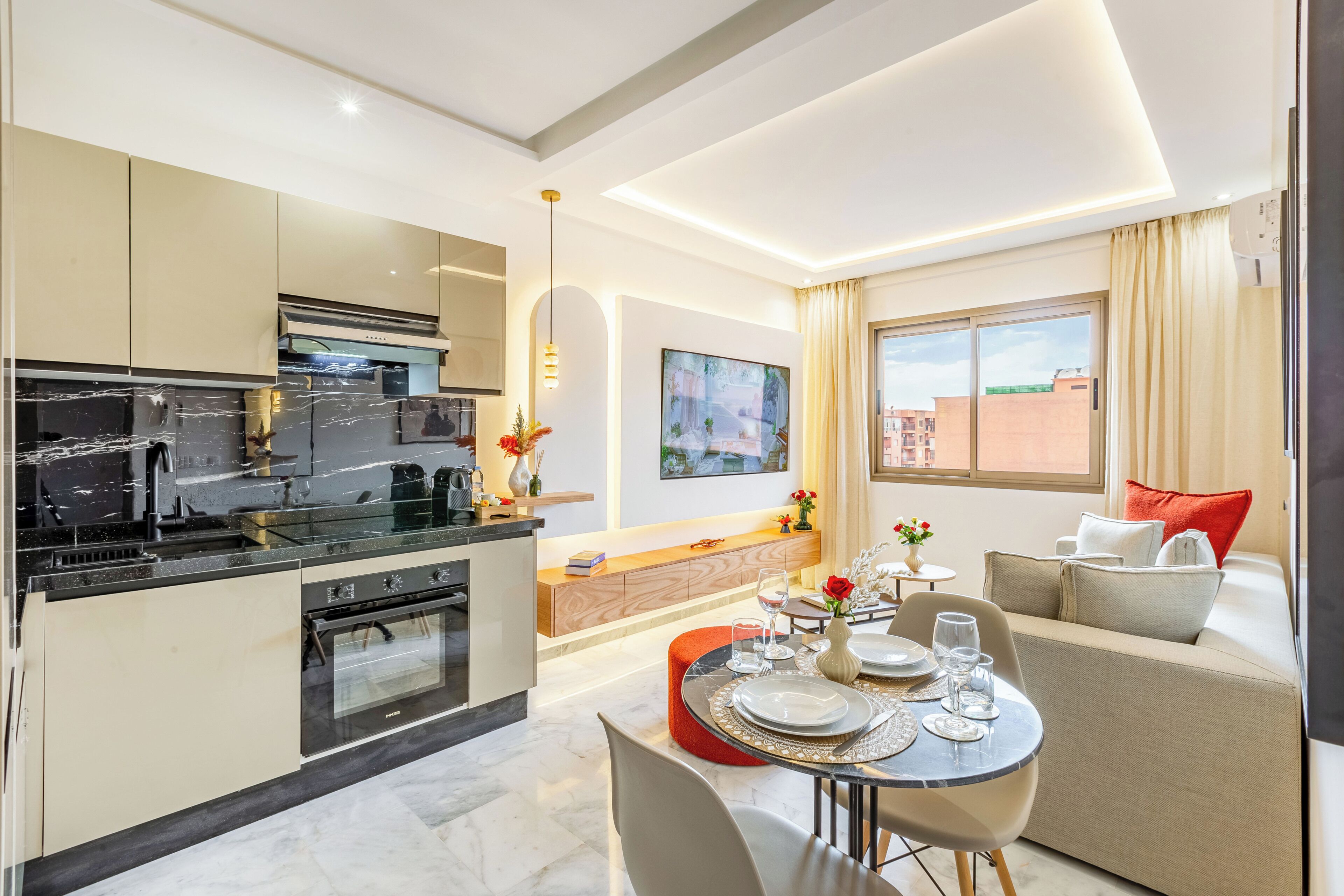 A modern kitchen with a dining area, a sofa, and a window with curtains.