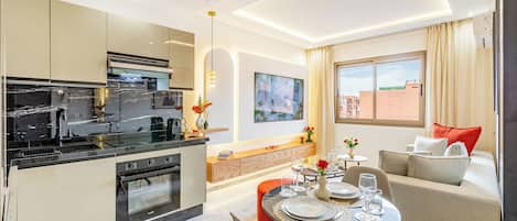 A modern kitchen with a dining area, a sofa, and a window with curtains.