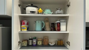 Een keukenkastje met een slowcooker, een waterkoker en verschillende levensmiddelen.
