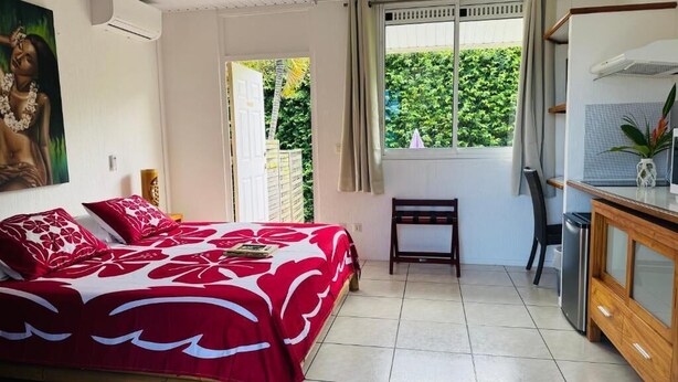 Un dormitorio con cama, escritorio, silla y ventana con vistas a la vegetación.