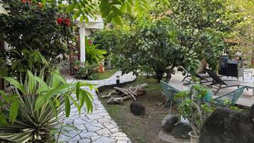 A garden pathway with a stone pavement leading to a seating area with a table and chairs.