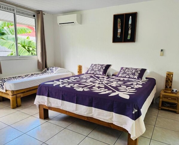 Una habitación con dos camas, una ventana con cortinas, un equipo de aire acondicionado y una obra de arte colgada en la pared.