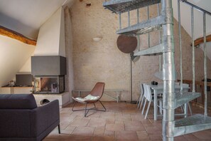 A modern living room with a fireplace, a spiral staircase, and a stone wall. - Charming duplex with a pool near Amboise, sleeps 5 (including 1 baby) (Pocé-sur-Cisse)