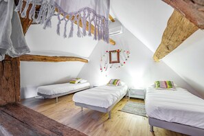 Ein Schlafzimmer mit schrägem Dach, Holzbalken und einem Bett mit weißer Bettwäsche.