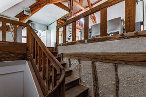 Eine hölzerne Treppe mit rustikalem Design, die zu einem Raum mit weißen Wänden und einer weißen Decke führt.