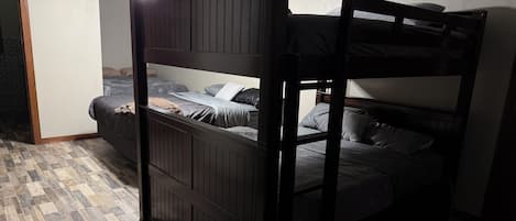 Een stapelbed met houten frame, een plafondventilator en een vloer met patroon.