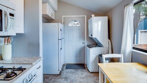 A compact kitchen with white appliances, a stove, a microwave, and a refrigerator.