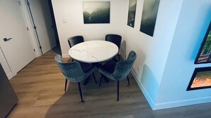 A dining area with a round table and four chairs, a door leading to another room, and three framed artworks on the wall. - Modern and Bright Lynn Valley Retreat (North Vancouver)