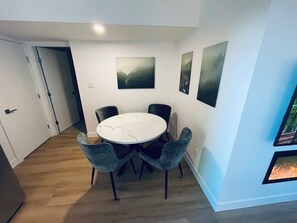 A dining area with a round table and four chairs, a door leading to another room, and three framed artworks on the wall. - Modern and Bright Lynn Valley Retreat (North Vancouver)