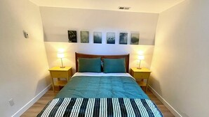 A bedroom with a bed, two bedside tables, a headboard, and wall-mounted artwork. - Modern and Bright Lynn Valley Retreat (North Vancouver)