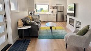 A modern living room with a sofa, a round coffee table, and a TV mounted on the wall. - Modern and Bright Lynn Valley Retreat (North Vancouver)