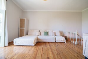 A bedroom with a wooden floor, a bed with white bedding, a tall wardrobe, and a staircase. - Meraki Villa Pelion Home to Home Management (Kalamos Magnesia)