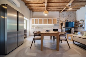 Eine moderne Küche mit Holzboden, einem integrierten Herd und einem Essbereich mit Tisch und Stühlen.