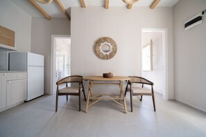 A modern kitchen with a dining table and chairs, a wall-mounted decorative mirror, and a view of the outside. - Meraki Villa Pelion Home to Home Management (Kalamos Magnesia)