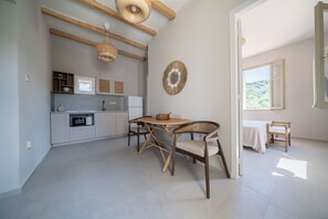Una cocina moderna con electrodomésticos integrados, un comedor con una mesa redonda y sillas, y vistas a través de un ventanal.