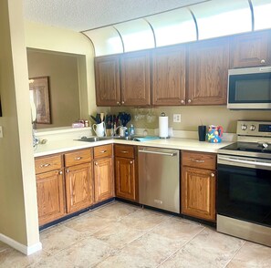 A kitchen with wooden cabinets, a dishwasher, a microwave, and a stove.